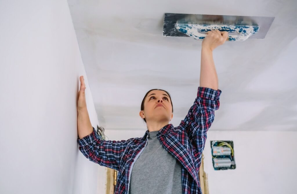 Bricklayer smoothing plaster ceiling with the trowel
